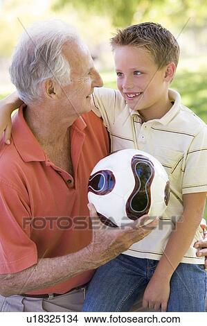 Picture - Grandfather and grandson outdoors with ball smiling. Fotosearch