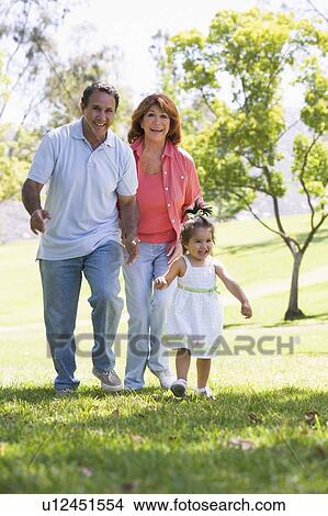 Picture - Grandparents walking in park with granddaughter. Fotosearch