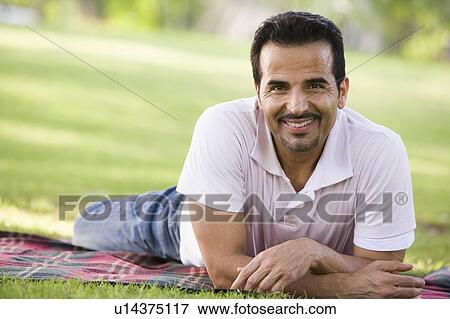 Stock Photo - Man lying outdoors at park smiling (selective focus). Fotosearch