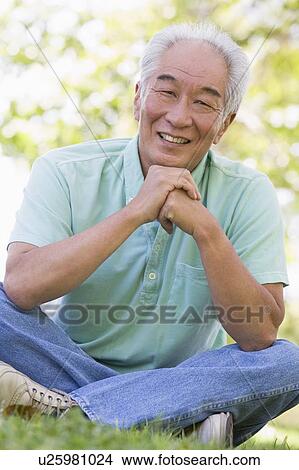 Man sitting outdoors smiling View Large Photo Image Picture - Man sitting outdoors smiling. Fotosearch