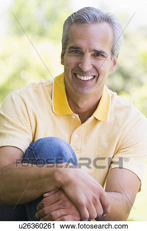 Man sitting outdoors smiling View Large Photo Image Stock Image - Man sitting outdoors smiling. Fotosearch
