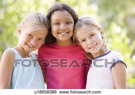 Three young girl friends standing outdoors smiling View Large Photo Image Stock Photograph - Three young girl friends standing outdoors smiling. Fotosearch