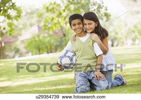 Two young children outdoors in park with ball smiling (selective focus) View Large Photo Image Stock Photo - Two young children outdoors in park with ball smiling (selective focus). Fotosearch