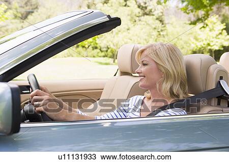 Woman in convertible car smiling View Large Photo Image Stock Image - Woman in convertible car smiling. Fotosearch