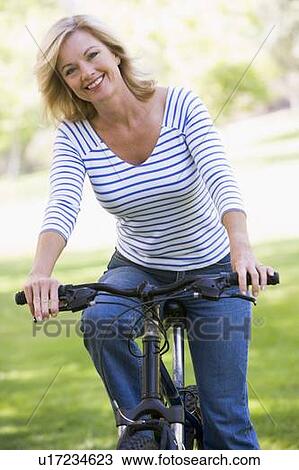 Woman on bike outdoors smiling View Large Photo Image Stock Image - Woman on bike outdoors smiling. Fotosearch