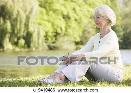 Stock Photograph - Woman outdoors at park by lake smiling. Fotosearch