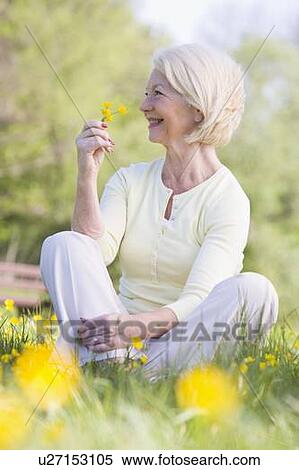 Woman sitting outdoors smiling and holding a Buttercup flower View Large Photo Image Stock Photography - Woman sitting outdoors smiling and holding a Buttercup flower. Fotosearch