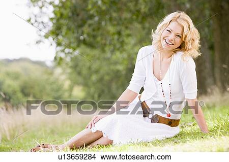 Woman sitting outdoors smiling View Large Photo Image Picture - Woman sitting outdoors smiling. Fotosearch