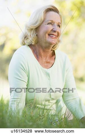 Woman sitting outdoors smiling View Large Photo Image Stock Photo - Woman sitting outdoors smiling. Fotosearch