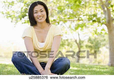 Woman sitting outdoors smiling View Large Photo Image Stock Photograph - Woman sitting outdoors smiling. Fotosearch