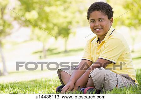 Young boy sitting outdoors smiling View Large Photo Image Stock Image - Young boy sitting outdoors smiling. Fotosearch