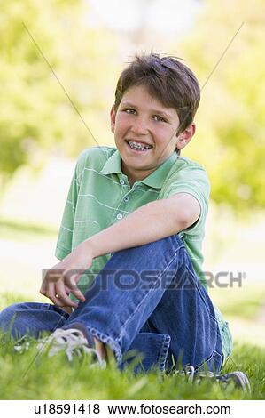 Young boy sitting outdoors smiling View Large Photo Image Stock Photo - Young boy sitting outdoors smiling. Fotosearch