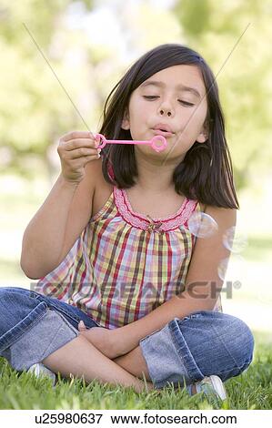 Stock Photo - Young girl blowing bubbles outdoors. Fotosearch