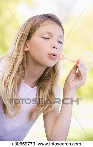 Young girl blowing bubbles outdoors View Large Photo Image Stock Photo - Young girl blowing bubbles outdoors. Fotosearch