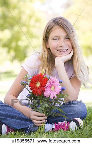 Young girl holding flowers and smiling View Large Photo Image Stock Image - Young girl holding flowers and smiling. Fotosearch