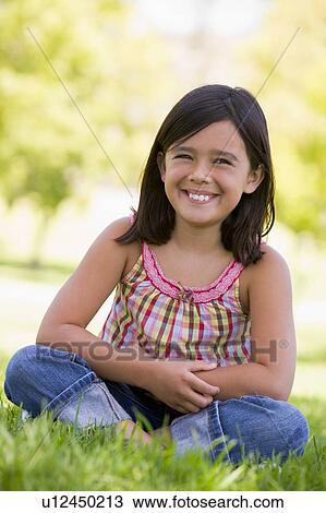 Young girl sitting outdoors smiling View Large Photo Image Stock Image - Young girl sitting outdoors smiling. Fotosearch