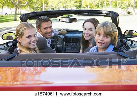 Stock Image - Family in convertible car smiling. Fotosearch