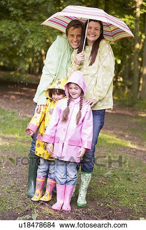 Picture - Family outdoors in rain with umbrella smiling. Fotosearch