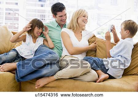 Family sitting in living room with digital camera smiling View Large Photo Image Stock Photograph - Family sitting in living room with digital camera smiling. Fotosearch