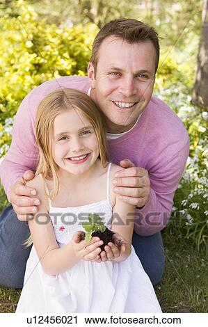 Father and daughter outdoors holding plant smiling View Large Photo Image Stock Image - Father and daughter outdoors holding plant smiling. Fotosearch