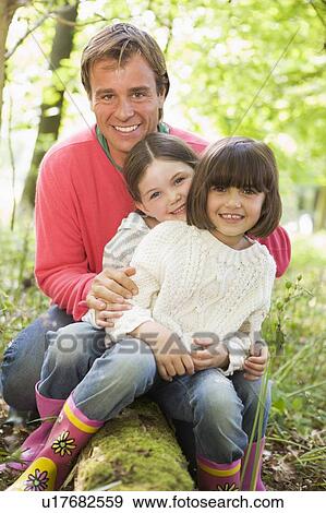 Father and daughters outdoors in woods sitting on log smiling View Large Photo Image Stock Photo - Father and daughters outdoors in woods sitting on log smiling. Fotosearch