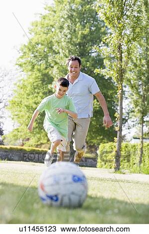 Man and young boy outdoors playing soccer and having fun View Large Photo Image Stock Image - Man and young boy outdoors playing soccer and having fun. Fotosearch
