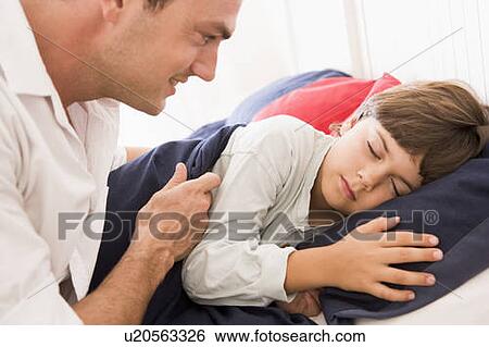Stock Photograph - Man waking young boy in bed smiling. Fotosearch