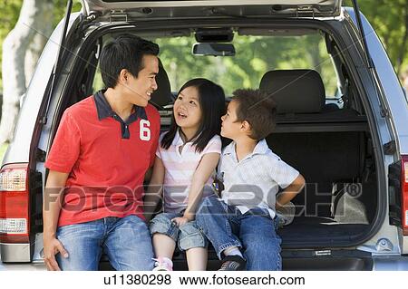 Stock Photo - Man with two children sitting in back of van smiling. Fotosearch