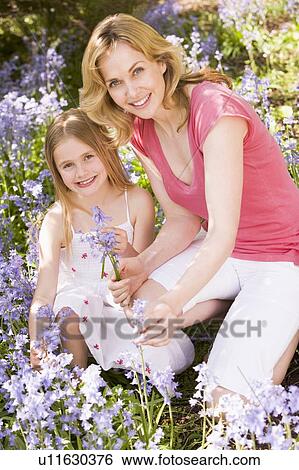 Stock Photograph - Mother and daughter outdoors holding flowers smiling. Fotosearch