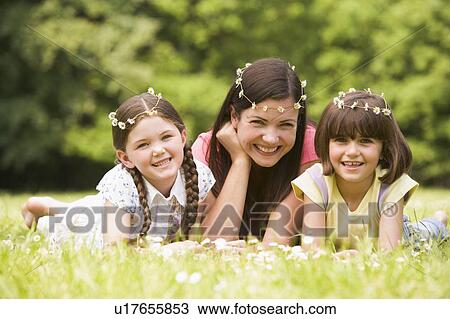 Mother and daughters lying outdoors with flowers smiling View Large Photo Image Stock Image - Mother and daughters lying outdoors with flowers smiling. Fotosearch
