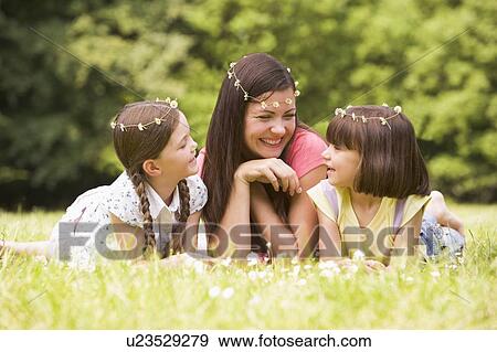Stock Photo - Mother and daughters lying outdoors with flowers smiling. Fotosearch