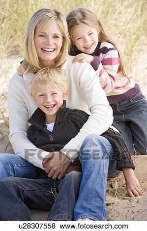 Mother and two young children sitting on beach smiling View Large Photo Image Stock Photo - Mother and two young children sitting on beach smiling. Fotosearch