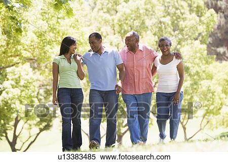 Stock Photography - Two couples walking outdoors arm in arm smiling. Fotosearch
