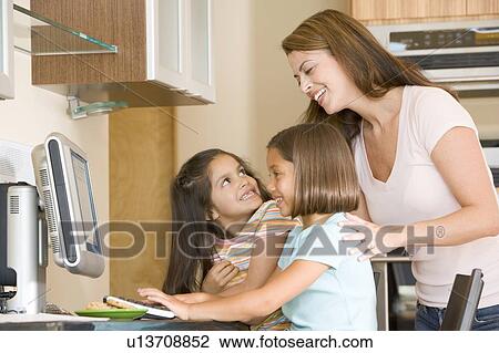 Woman and two young girls in kitchen with computer smiling View Large Photo Image Stock Image - Woman and two young girls in kitchen with computer smiling. Fotosearch