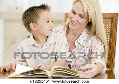 Woman and young boy reading book in dining room smiling View Large Photo Image Stock Image - Woman and young boy reading book in dining room smiling. Fotosearch