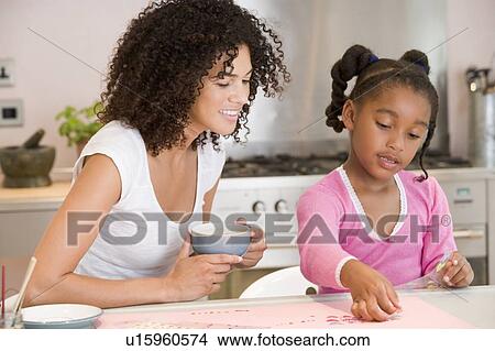Picture - Woman and young girl in kitchen with art project smiling. Fotosearch