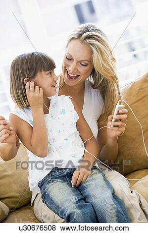 Stock Photo - Woman and young girl in living room with MP3 player smiling. Fotosearch