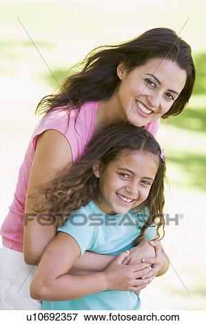 Stock Photo - Woman and young girl outdoors embracing and smiling. Fotosearch