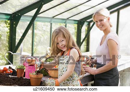 Young girl and woman in greenhouse putting soil in pots smiling View Large Photo Image Stock Image - Young girl and woman in greenhouse putting soil in pots smiling. Fotosearch