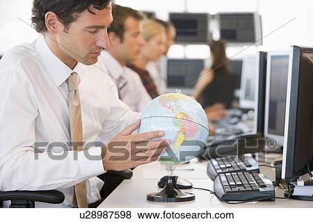 Stock Photo - Businessman in office space with a desk globe. Fotosearch
