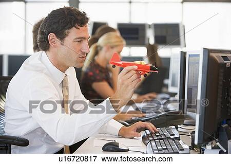 Businessman in office space with a toy airplane View Large Photo Image Stock Photo - Businessman in office space with a toy airplane. Fotosearch
