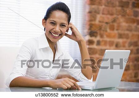 Businesswoman in office with laptop laughing View Large Photo Image Stock Image - Businesswoman in office with laptop laughing. Fotosearch