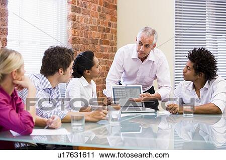 Stock Image - Five businesspeople in boardroom with laptop. Fotosearch