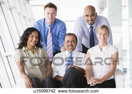Stock Image - Five businesspeople indoors smiling (high key/selective focus). Fotosearch