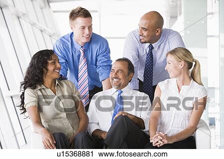 Stock Image - Five businesspeople indoors smiling (high key/selective focus). Fotosearch