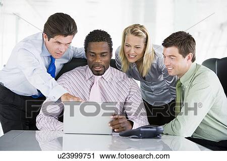 Four businesspeople in a boardroom pointing at laptop and smiling View Large Photo Image Stock Image - Four businesspeople in a boardroom pointing at laptop and smiling. Fotosearch