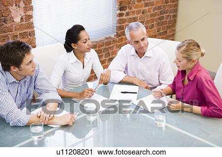 Stock Image - Four businesspeople in boardroom talking. Fotosearch