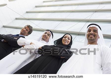 Four businesspeople standing outdoors by building smiling (selective focus) View Large Photo Image Stock Image - Four businesspeople standing outdoors by building smiling (selective focus). Fotosearch