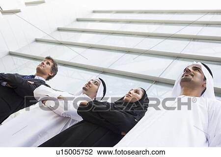 Four businesspeople standing outdoors by building (selective focus) View Large Photo Image Stock Image - Four businesspeople standing outdoors by building (selective focus). Fotosearch