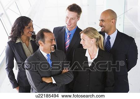 Group of co-workers standing in office space smiling (high key) View Large Photo Image Picture - Group of co-workers standing in office space smiling (high key). Fotosearch